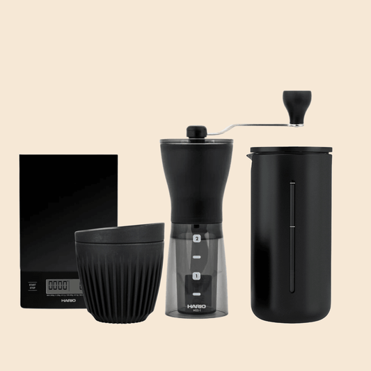 A french press hand grinder bundle that comes with a hand grinder, a french press, a huskee resuable cup and a Hario scale