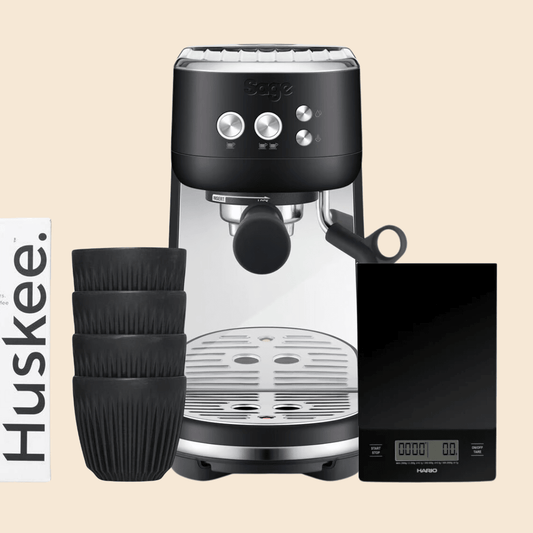 A sage bambino home barista bundle that comes with a Sage Bambino espresso machine, four Huskee reusable coffee cups and a Hario scale 